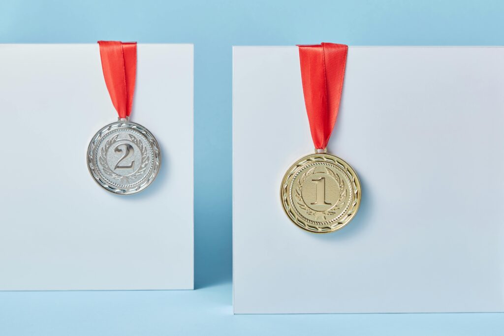Gold and silver medals with red ribbons against a blue backdrop representing achievement and success.