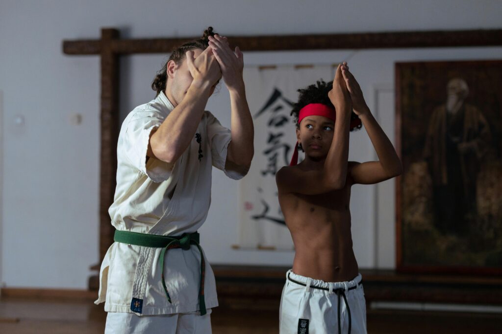Young boy practicing karate with a trainer inside a dojo.
